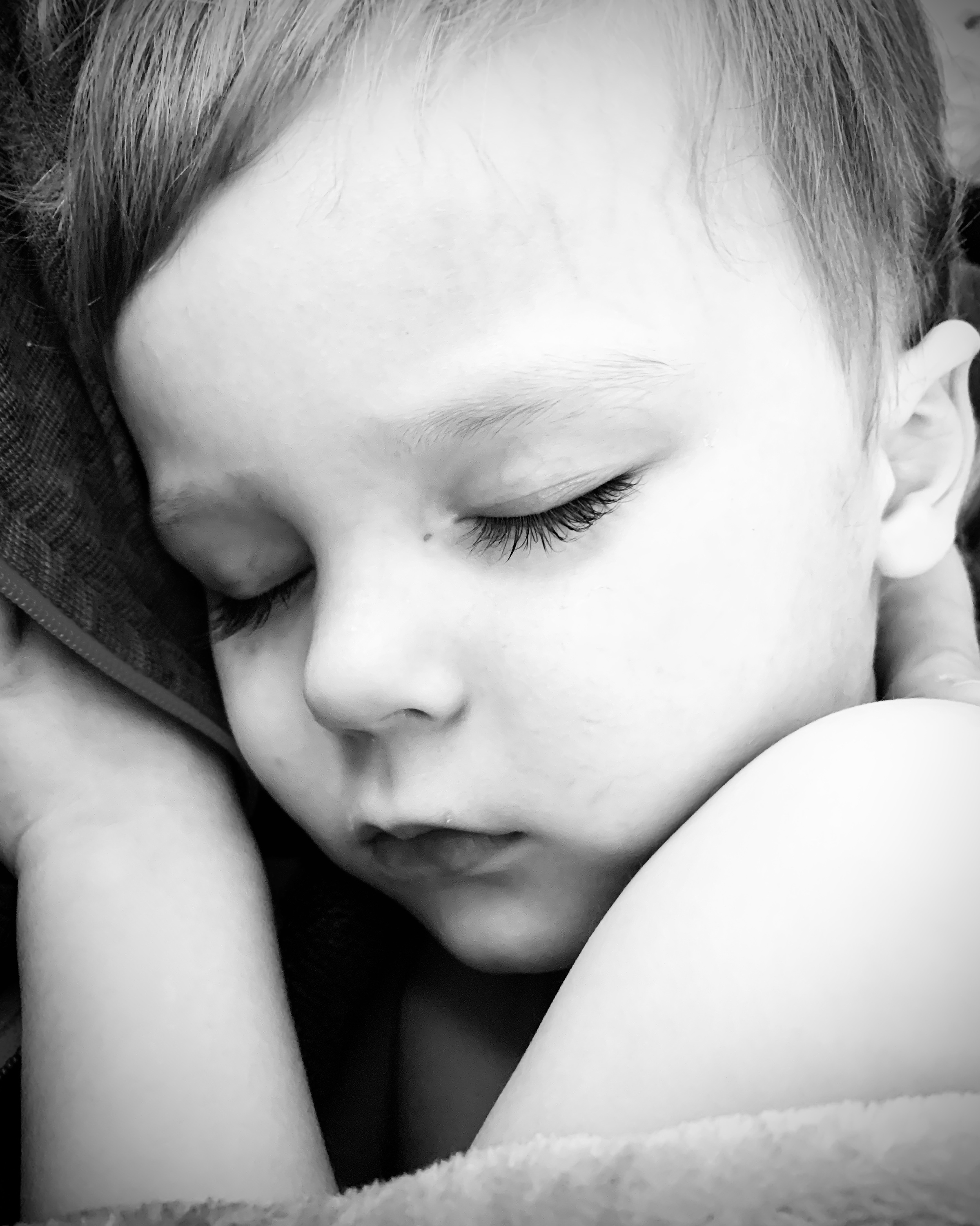 A sleeping child cradled in a caregiver's arms