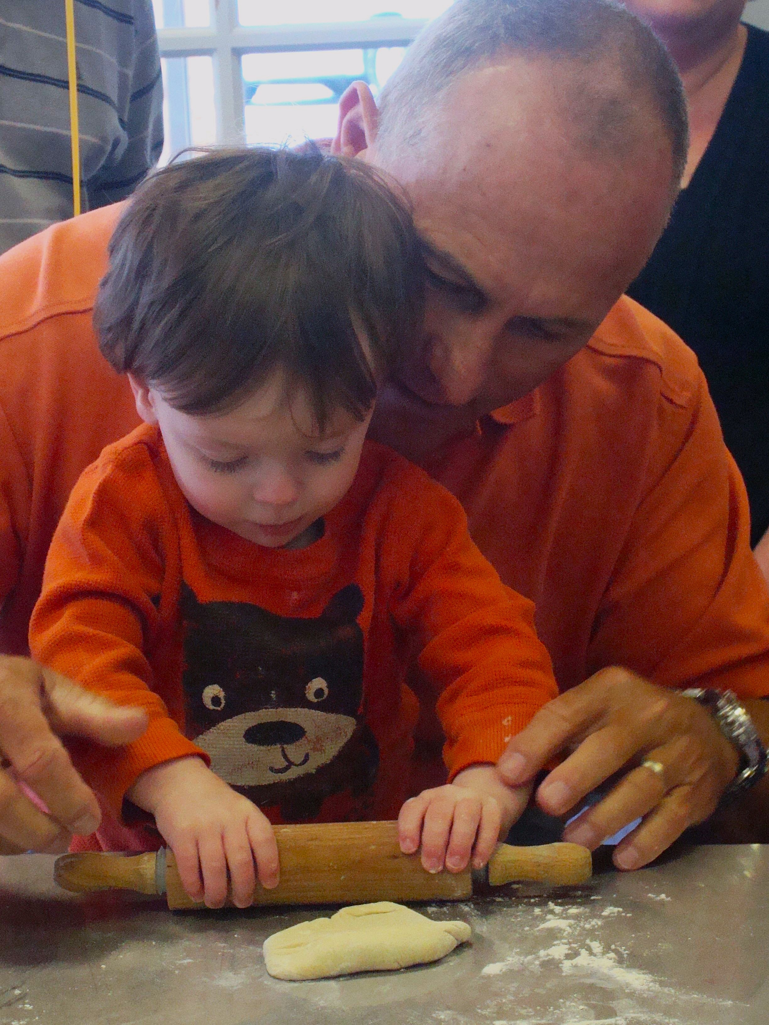 A grandfather helping his grandson make a pizza