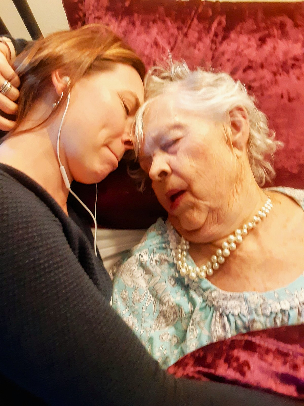 A grandmother wearing her pearls, comforted by family at the end of life